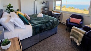 Une chambre à coucher avec un lit, un bureau, une chaise et une vue sur la mer.