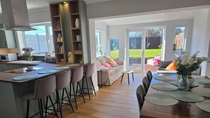 Une cuisine moderne dotée d’un îlot central, de tabourets de bar et d’un coin repas avec une table dressée pour quatre personnes.