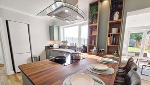 Une cuisine moderne dotée d’un îlot central, d’appareils électroménagers intégrés et donnant sur le jardin.