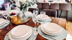 Une table à manger dressée avec des assiettes, des verres et un vase rempli de fleurs.