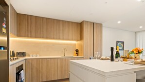 A modern kitchen with wooden cabinetry, a central island, and a built-in oven.