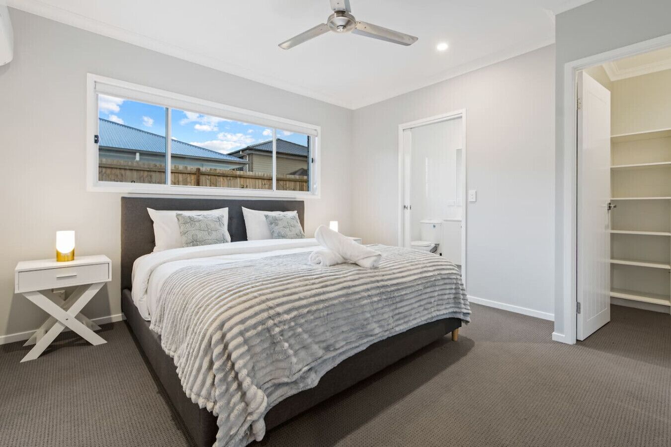 A bedroom with a bed, bedside table, and a ceiling fan.