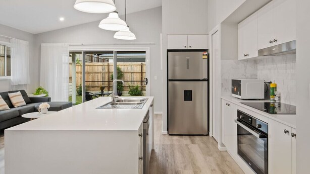 A modern kitchen with a central island, stainless steel appliances, and pendant lighting. - Newly Built 4BR Family Oasis | Comfort & Space (Logan Reserve)