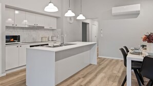 A modern kitchen with white cabinetry, a central island, and pendant lighting. - Newly Built 4BR Family Oasis | Comfort & Space (Logan Reserve)