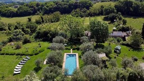 An aerial view of a property with a swimming pool surrounded by lush greenery, a few buildings, and a clear sky. - La Cervaiola  (Porano)