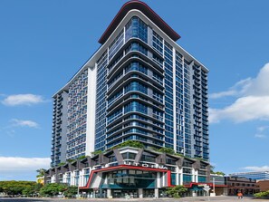 Un hotel moderno de gran altura, con un diseño llamativo, una entrada destacada y varios balcones.