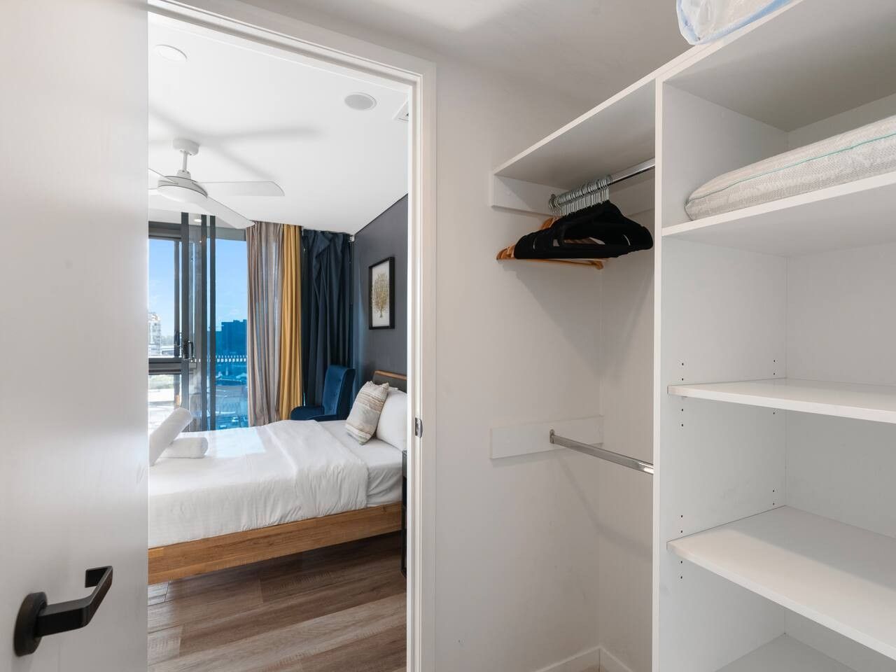 Una habitación de hotel con una cama, un armario y vistas a la ciudad.