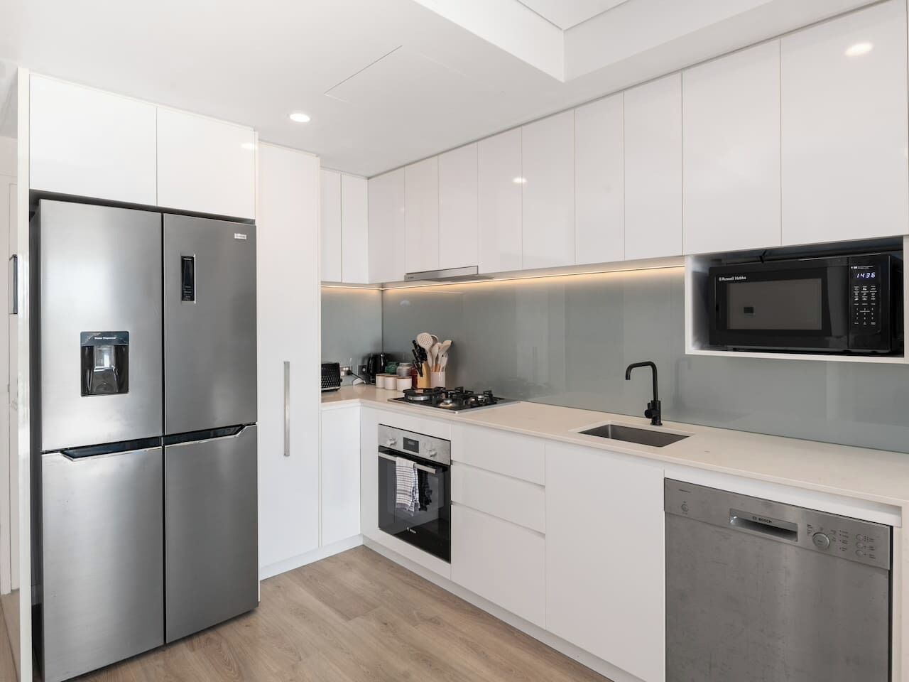 Een moderne keuken met roestvrijstalen apparatuur, witte kastjes en een vaatwasser.