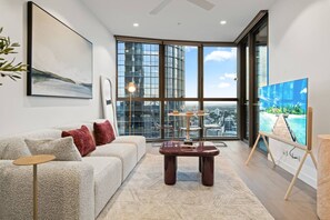 A modern living room with a sofa, coffee table, and a painting on easel.