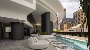 A modern rooftop pool area with a curved seating area and a pool.