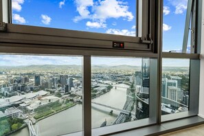 Panoramisch uitzicht vanuit een hoog raam op een stadsgezicht met een rivier, bruggen en moderne gebouwen.