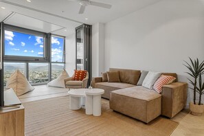 A modern living room with a large window, a sofa, a chair, and a coffee table.