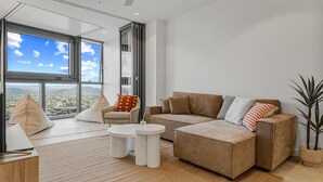 A modern living room with a large window, a sofa, a chair, and a coffee table.