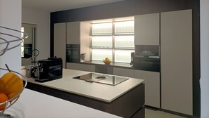 A modern kitchen with a central island, built-in appliances, and a window with frosted glass.