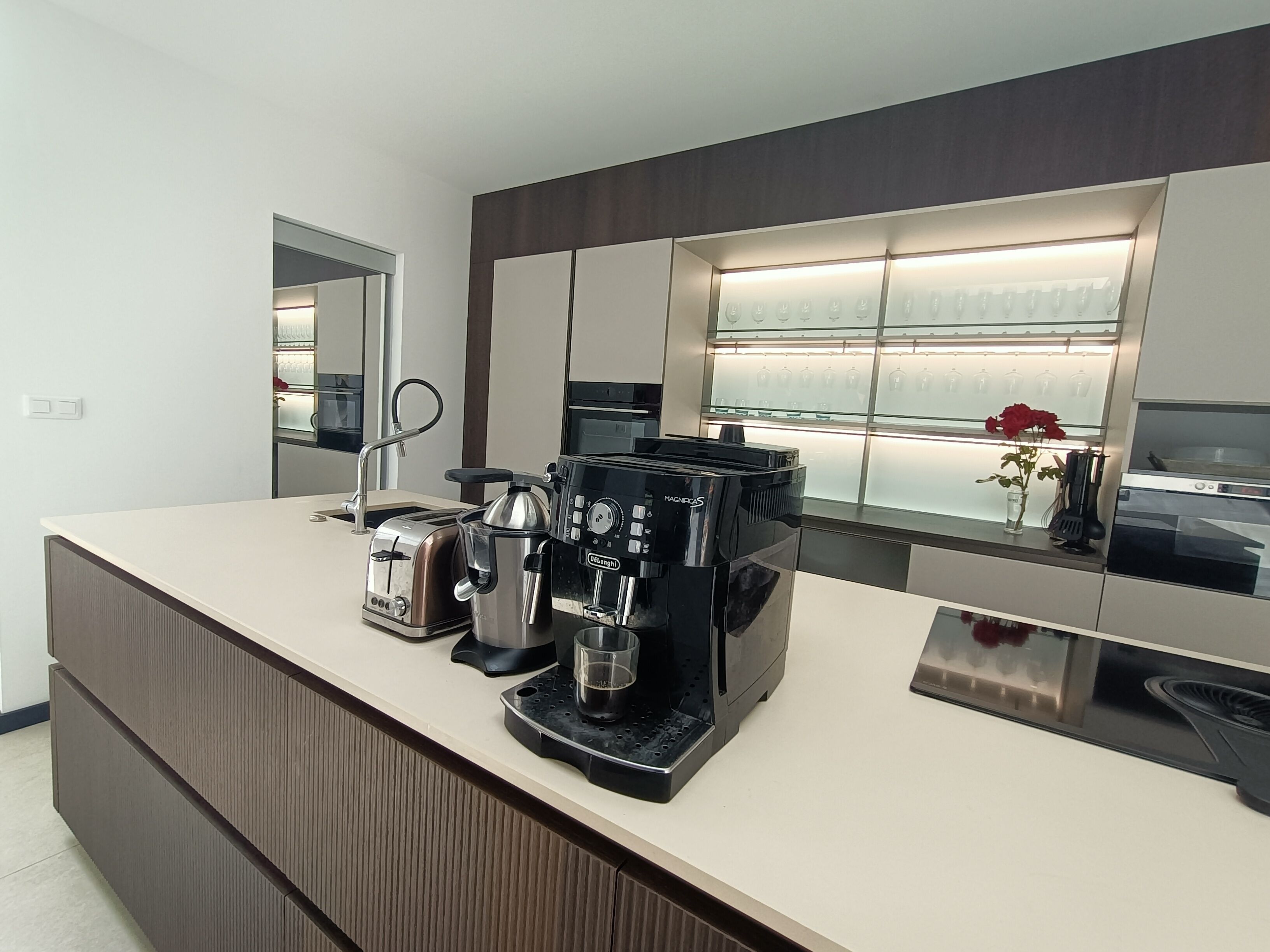 A modern kitchen with a built-in coffee maker, a toaster, and a kettle on the counter.