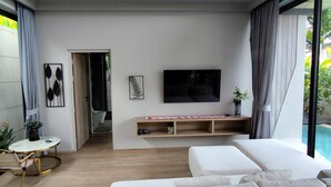 Una sala de estar moderna con un sofá grande, un televisor de pantalla plana y techo de madera.