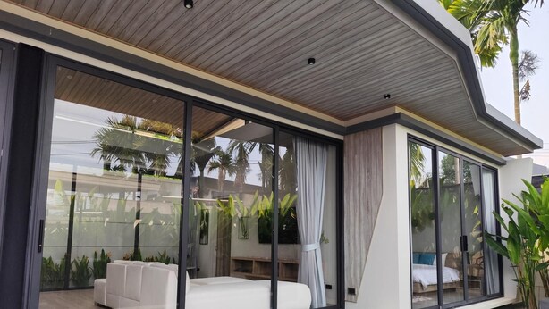 Una casa moderna con un amplio ventanal, una piscina y un sofá blanco.