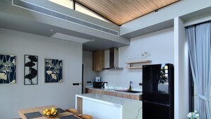 Una cocina moderna con una isla de mármol, techo de madera y un comedor con mesa y sillas.