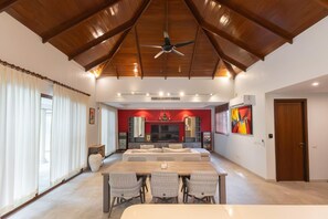 A spacious living area with a high ceiling, a central seating arrangement, and a television.