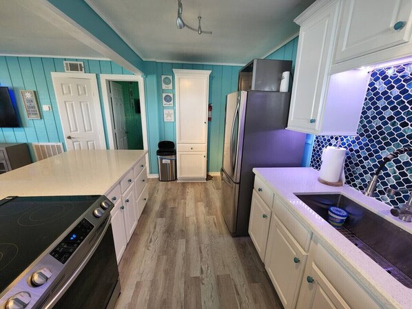 A kitchen with teal walls, white cabinets, a stainless steel refrigerator, and a black stove.