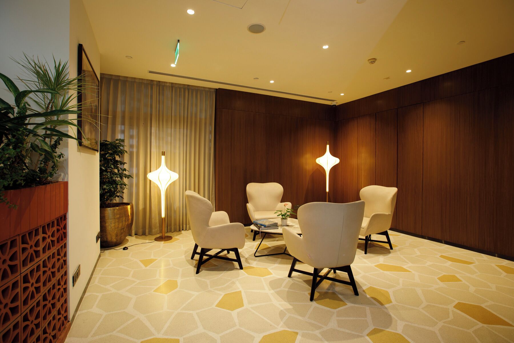 A conference room with four chairs, a table, and two floor lamps.