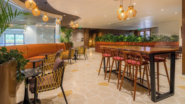 Eine moderne Bar mit Sitzgelegenheiten, Pendelleuchten und Topfpflanzen.