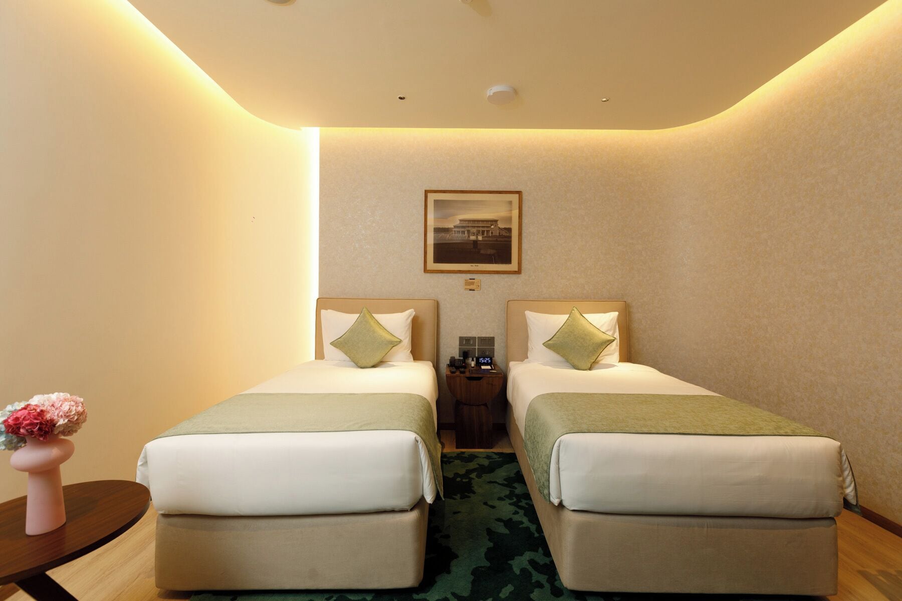 A hotel room with two beds, a nightstand, a clock, and a framed picture on the wall.