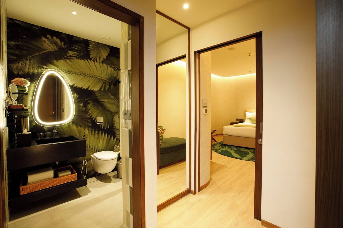 Un baño moderno con un espejo grande, inodoro y lavamanos.