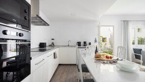 Une cuisine moderne avec des meubles blancs, une cuisinière noire et un coin repas avec une table dressée pour deux personnes.