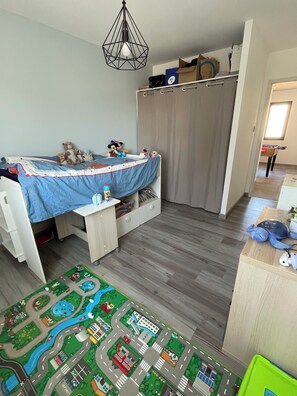 A child's bedroom with a bunk bed, a desk, and a play mat.