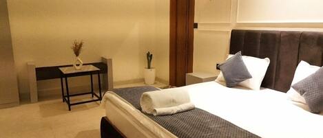 A hotel room with a bed, bedside table, and a small potted plant.