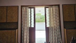 Une pièce dotée d’une grande porte coulissante donnant sur un balcon, d’armoires en bois et de rideaux à motifs.