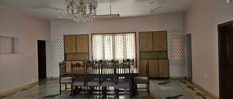 A spacious room with a dining table and chairs, a chandelier, and a patterned floor.