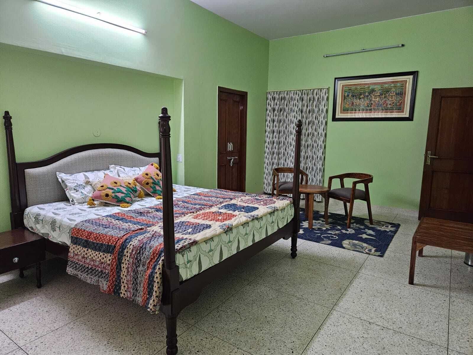 A bedroom with a four-poster bed, a wooden nightstand, a chair, and a small table.