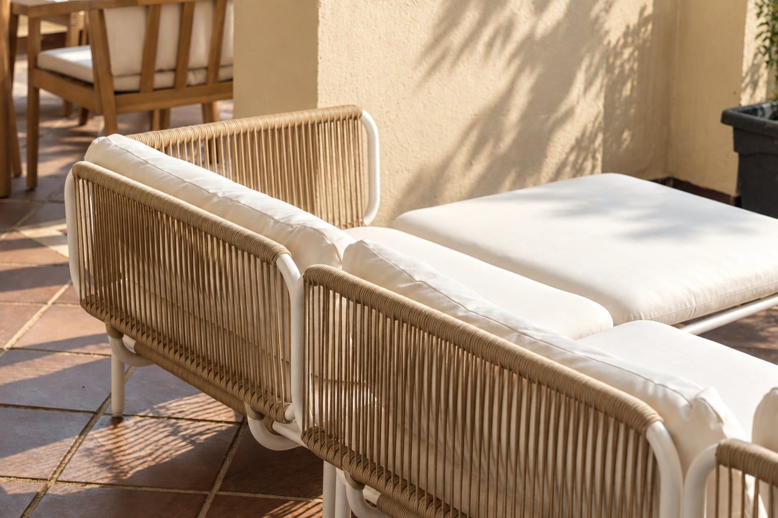 Un fauteuil de jardin en osier, doté d’un coussin, placé sur une terrasse carrelée.