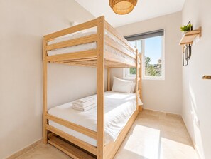 A bunk bed room with a window, a hanging light fixture, and a small shelf with a plant. - Sea & Sun Hills | Sea Views Pool (Estepona)