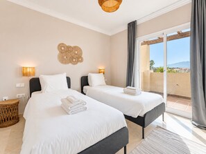 A hotel room with two beds, a balcony with a view, and a decorative wall piece.
