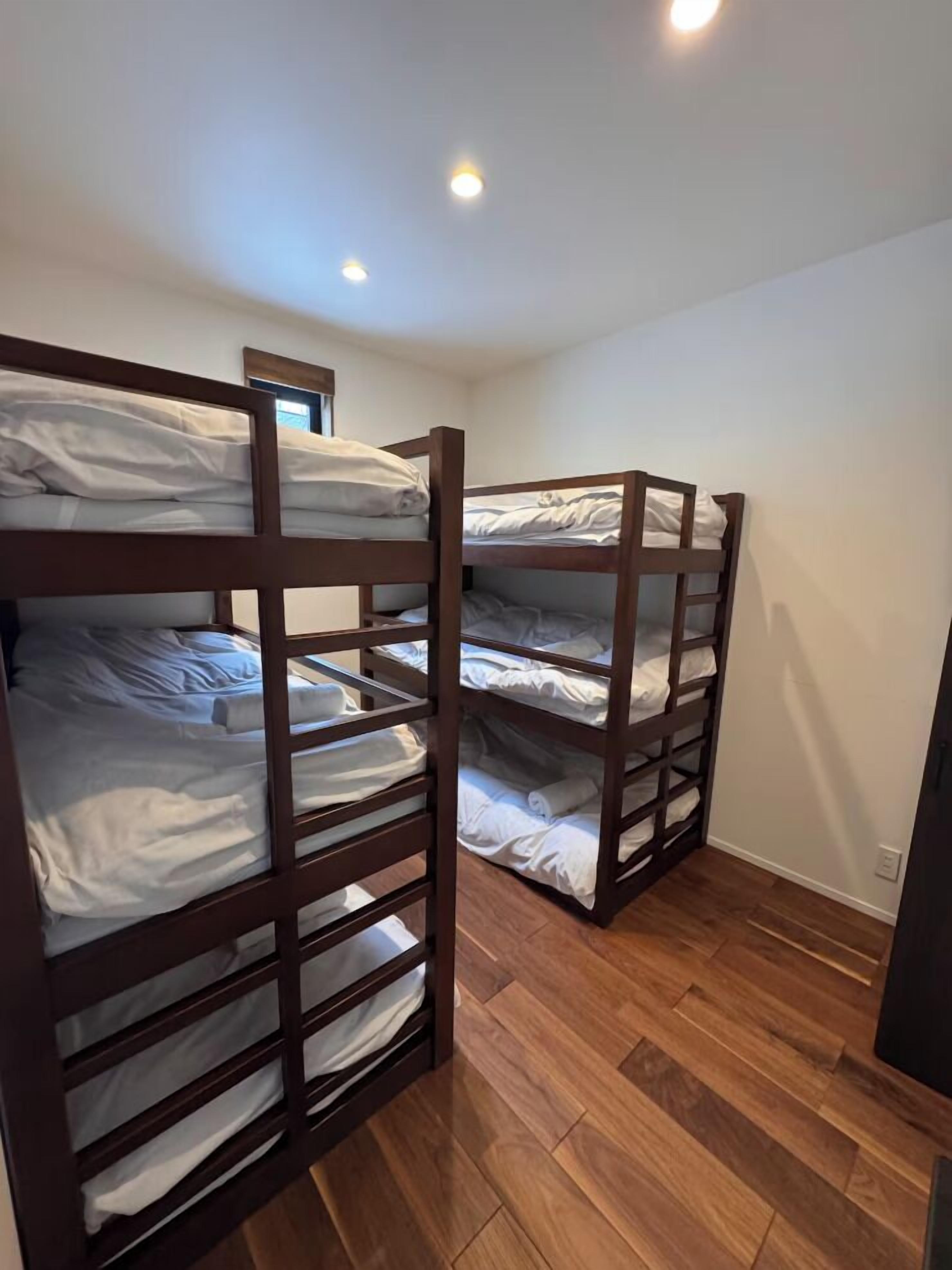 Ein Zimmer mit zwei Etagenbetten, Holzboden und Einbauleuchten.