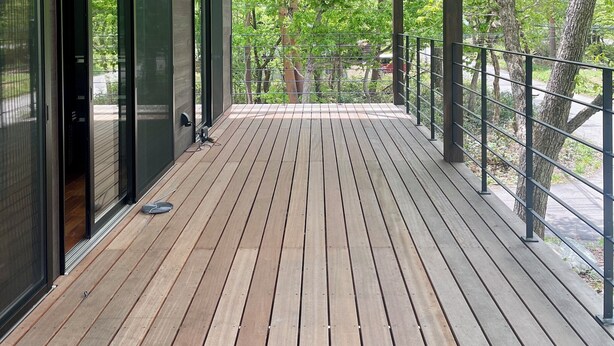 A wooden deck with a railing, large windows, and a view of trees. - Forest Gardens (Hakuba)
