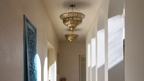 A hallway with patterned floor tiles, a hanging ornate chandelier, and a framed artwork on the wall. - Riad Romeo (Marrakech)