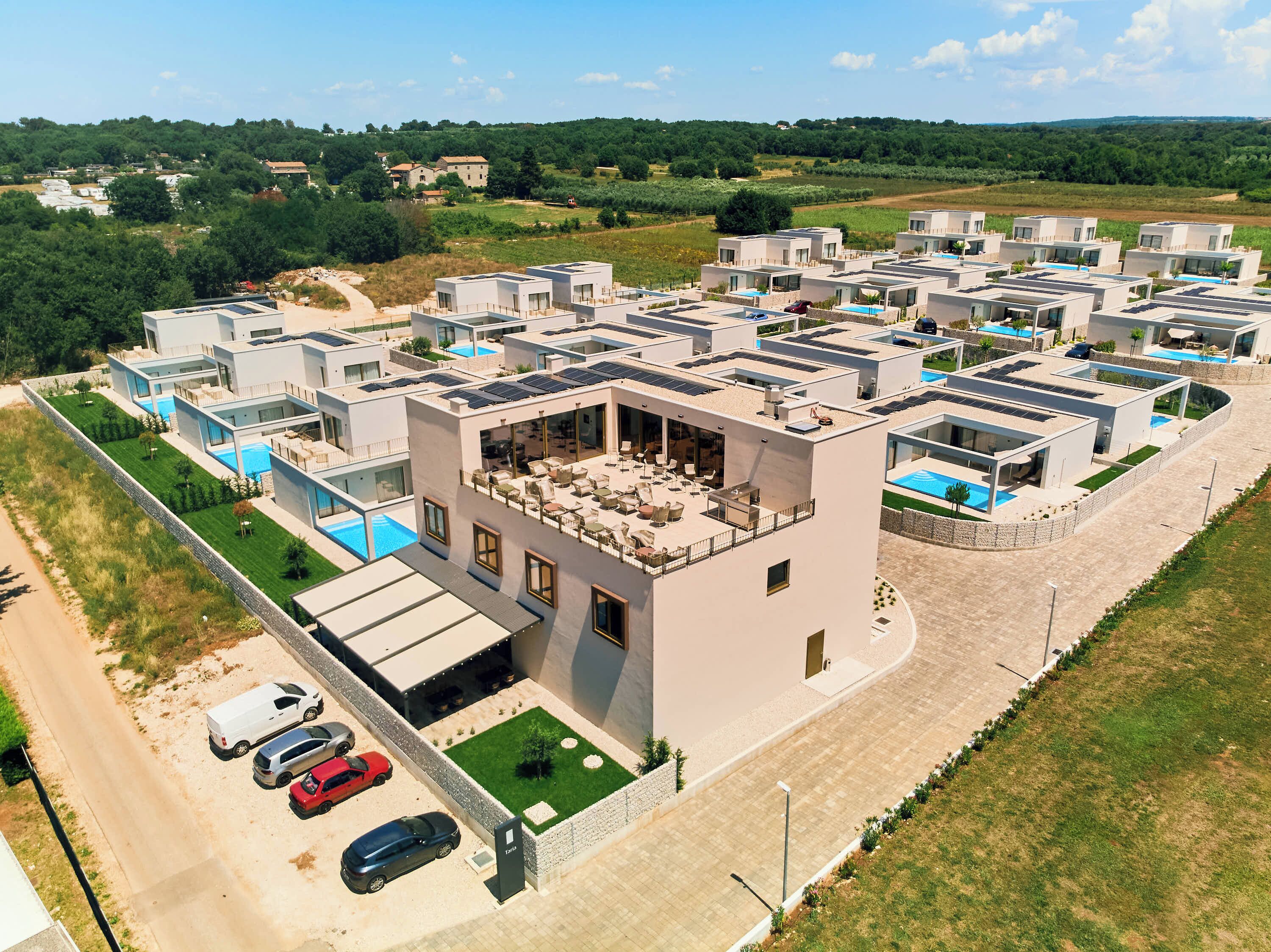Ein moderner Wohnkomplex mit mehreren Gebäuden, einem Innenhof und einem Swimmingpool.