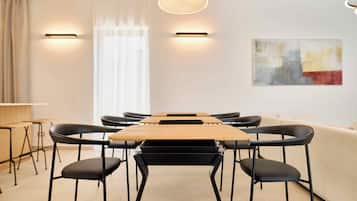 A modern conference room with a long table, black chairs, and a beige sofa.