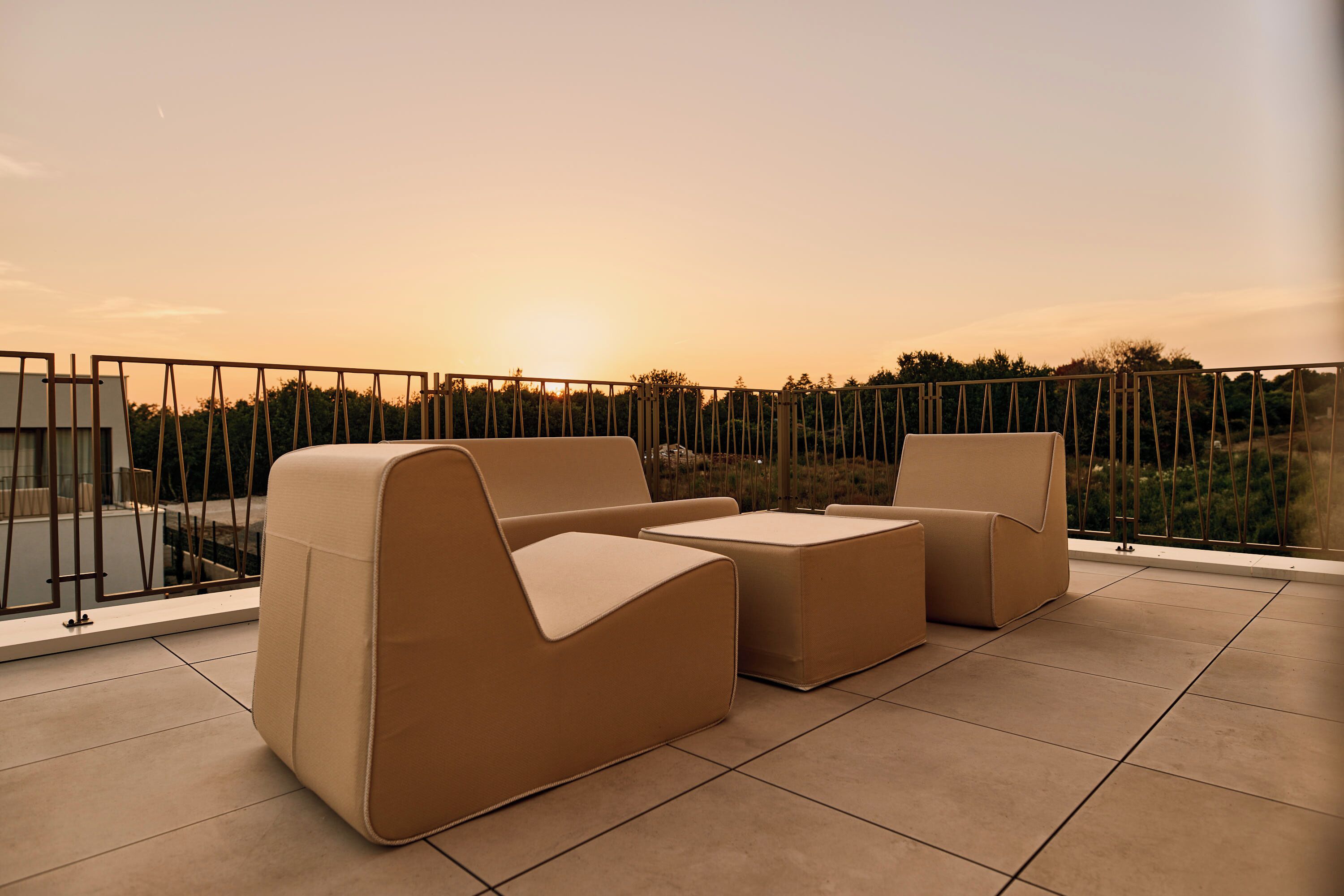 Una terraza con un conjunto de sofás, una mesa y vistas al atardecer.