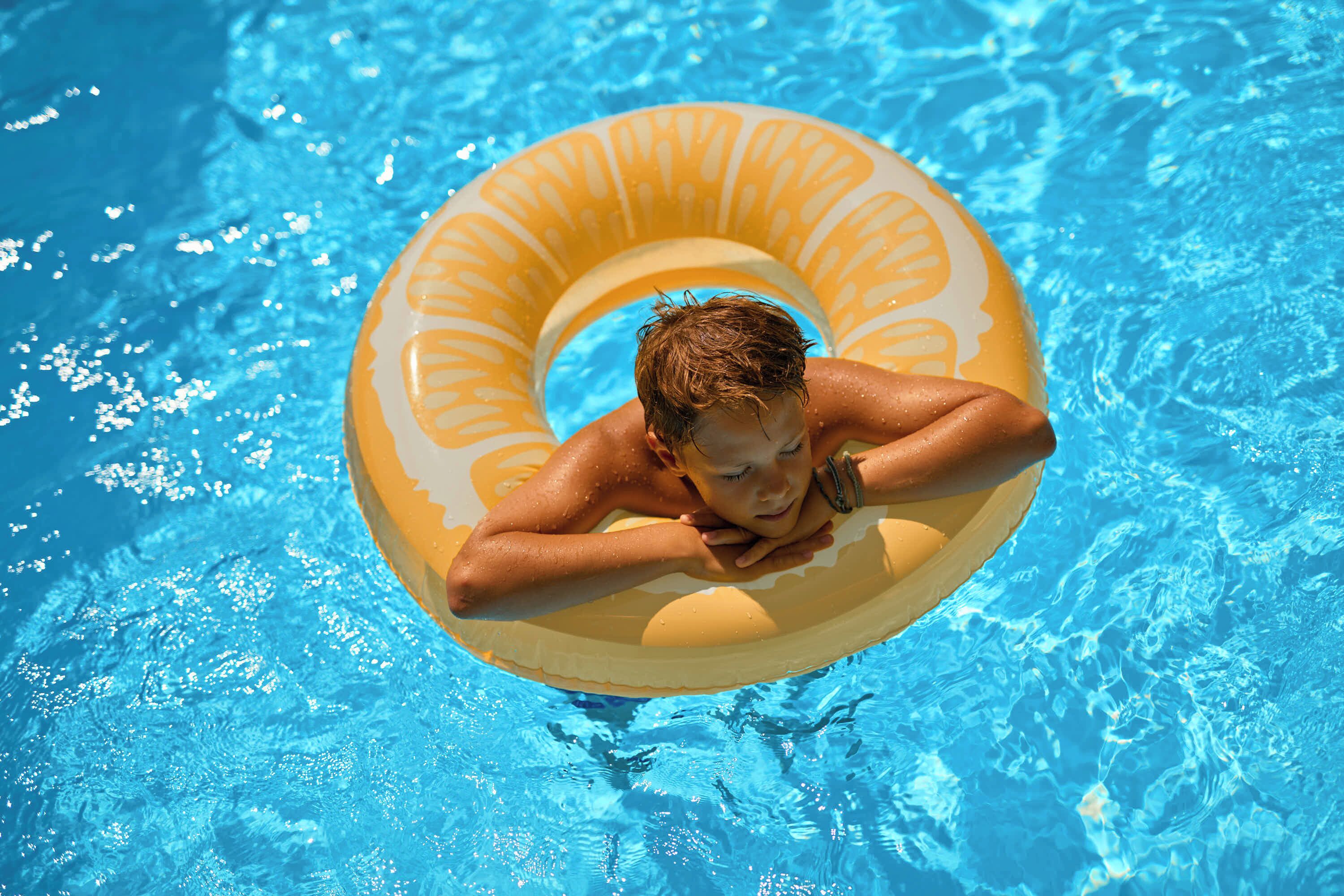 Una persona flota en una piscina sosteniendo un flotador amarillo.