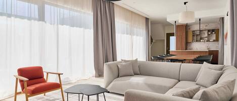 Una sala de estar moderna con un sofá seccional, un sillón rojo y una mesita.