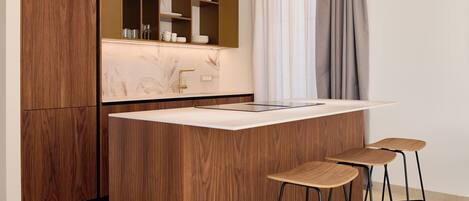 Una cocina moderna con una isla central, armarios de madera y taburetes de bar.