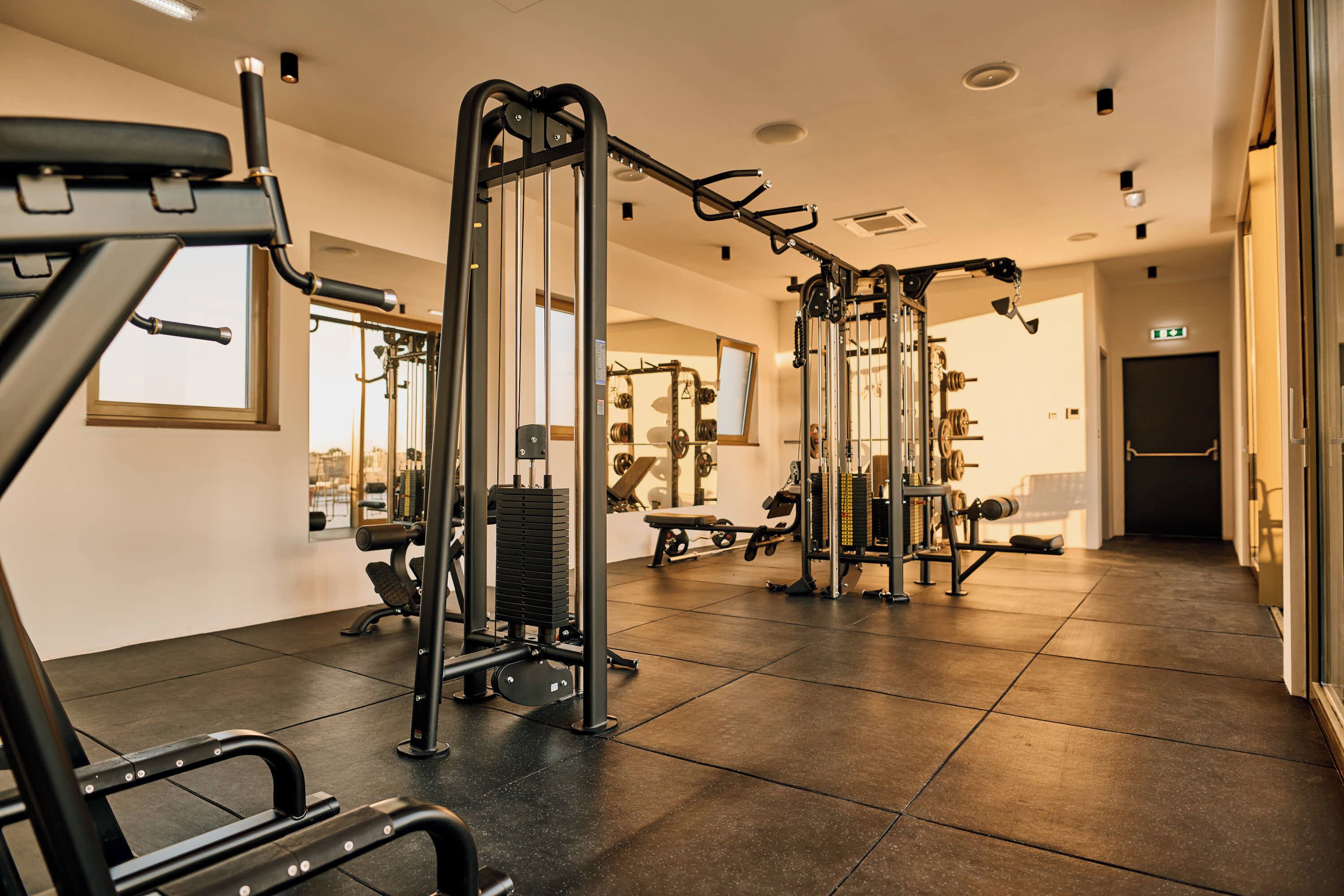 A gym with various exercise equipment, a large mirror, and a window.