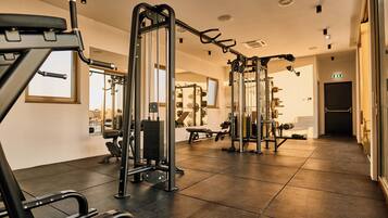 A gym with various exercise equipment, a large mirror, and a window.