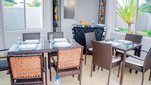 A dining area with wicker chairs and a glass table set for four. - Plavender inn (Dar es Salaam)