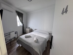 A bedroom with a bed, a desk, a dresser, and a window with curtains. - MÜDE Hostel (Torremolinos)